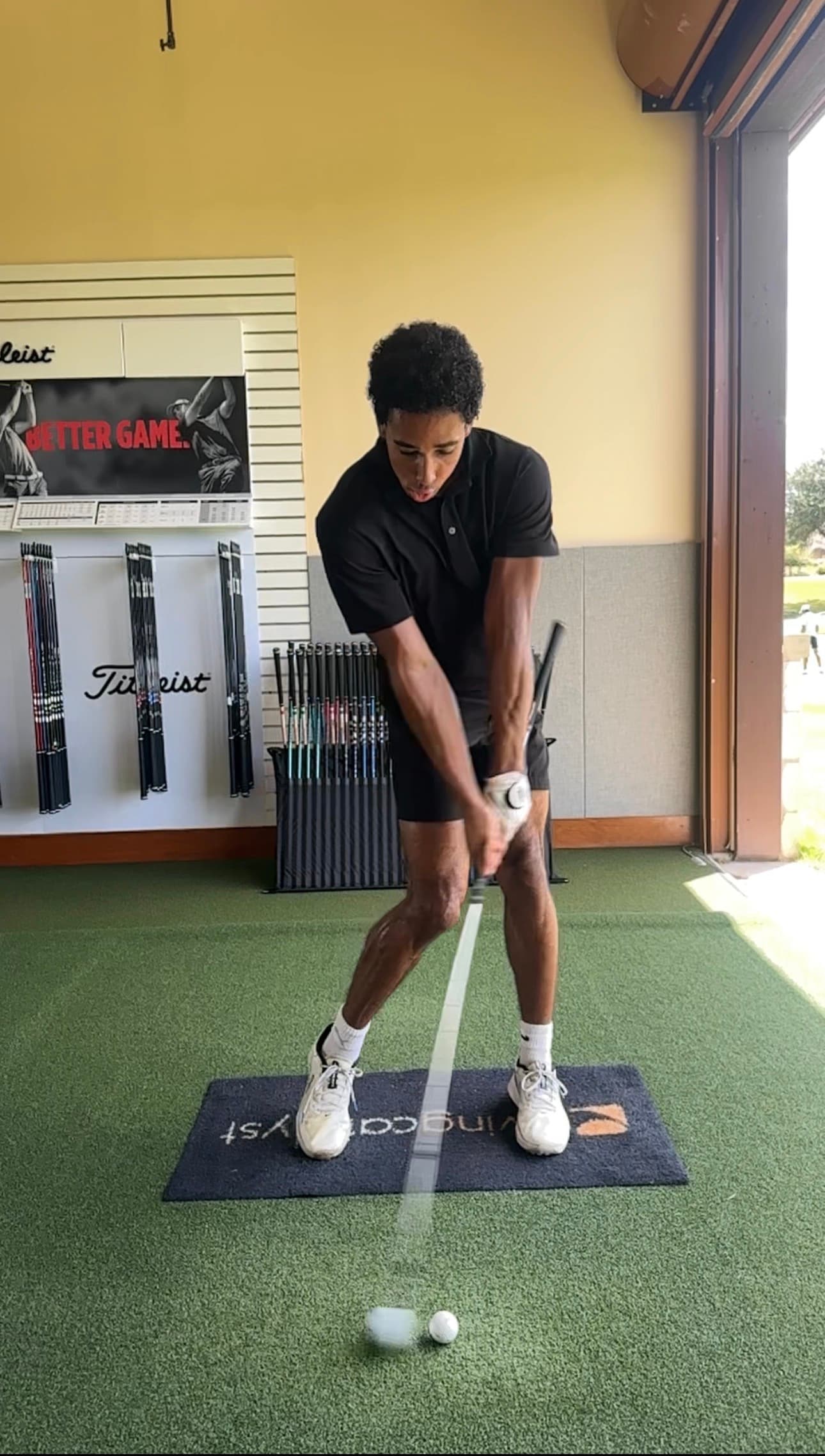 A golfer practicing forward shaft lean during a lesson in the hitting bay